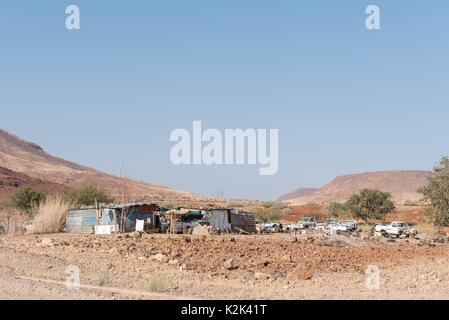 BERGSIG, NAMIBIA - 28. JUNI 2017: eine Straße Szene mit Baracken und Autowracks in Bergsig, einem kleinen Dorf in der Kunene Region von Namibia Stockfoto