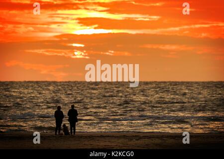 Southport, Merseyside, 30. August 2017. UK Wetter. Ein paar und ihrem Hund beobachten Sie den Sonnenuntergang über Horizont der Irischen See vom Strand in Southport, Merseyside. Credit: cernan Elias/Alamy leben Nachrichten Stockfoto