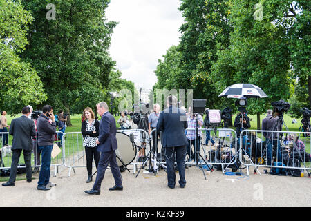 Ein Nachrichten Reporter und Kameramann mit einem Stück zu Kamera vor den Toren des Kensington Palace. Erinnerung an Prinzessin Diana, 20 Jahre nach ihrem Tod. Stockfoto