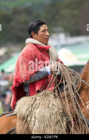 Juni 3, 2017 Machachi, Ecuador: Nahaufnahme von indigenen Quechua Cowboy zu Pferd gekleidet traditionell Holding leder Lasso auf dem Pferderücken Stockfoto