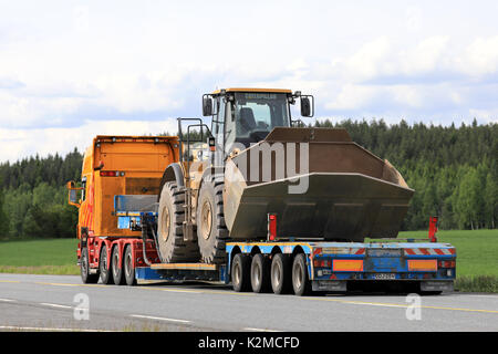 JOKIOINEN, Finnland - 16. JUNI 2017: Maßgeschneiderte Scania G 580 Lkw gooseneck Trailer der PHP Group Transporte große Cat 980H Radlader entlang der Autobahn a Stockfoto