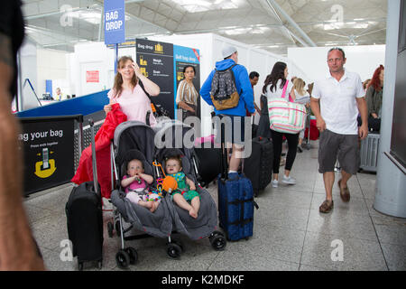 Fliegen mit zwei Mädchen im Doppelbuggy am Flughafen, London Stansted Stockfoto