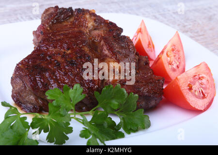 Gegrilltes Rindersteak mit Tomaten, und heißen asiatischen Chili Knoblauch Sauce auf dem Teller auf hölzernen Hintergrund Stockfoto