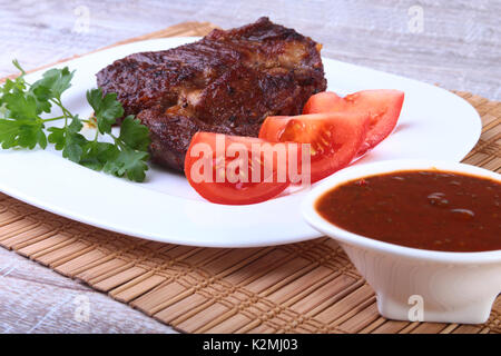 Gegrilltes Rindersteak mit Tomaten, und heißen asiatischen Chili Knoblauch Sauce auf dem Teller auf hölzernen Hintergrund Stockfoto