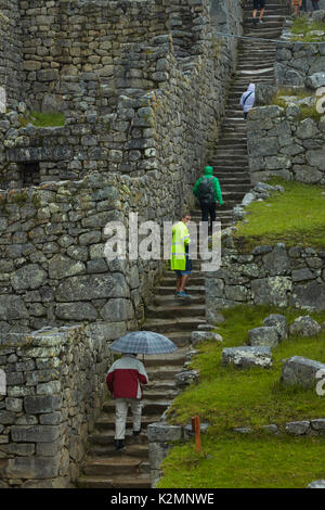 Touristen auf Steintreppe in den Regen, Machu Picchu Inka Ruinen (Weltkulturerbe), das Heilige Tal, Peru, Südamerika Stockfoto