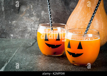 Ideen für eine Kinder- und Partei der Halloween Festlichkeiten. Kürbis orange Cocktail in Gläsern, mit einem Kürbis jack Lantern eingerichtet, auf einen schwarzen Stein Tabl Stockfoto