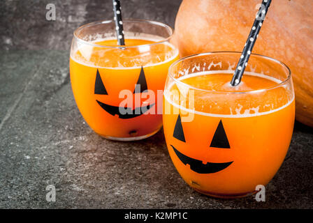 Ideen für eine Kinder- und Partei der Halloween Festlichkeiten. Kürbis orange Cocktail in Gläsern, mit einem Kürbis jack Lantern eingerichtet, auf einen schwarzen Stein Tabl Stockfoto