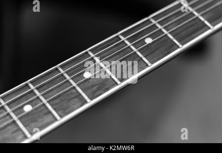 Nahaufnahme einer Gitarre Hals, der ist auch ein Griffbrett mit Strings in Schwarz-weiß Stil genannt. Stockfoto