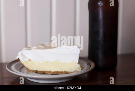 Scheibe Lemon Meringue Pie und eine Flasche Bier Stockfoto