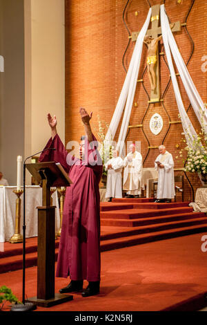 Ein Kantor führt die Versammlung im Gebet während einer Messe durch einen katholischen Bischof in eine Kathedrale in Orange, CA. Stockfoto