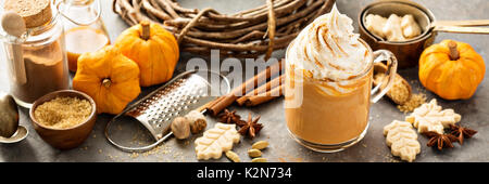 Pumpkin spice Latte in einem Glas Becher mit Zimt, Muskatnuss und Cookies Stockfoto