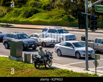 Auf einem Motorrad befestigt, ein Polizist versteckt sich hinter einem Utility Box an einer Ampel auf der Suche nach verkehrssuender in Laguna Niguel, CA. Stockfoto