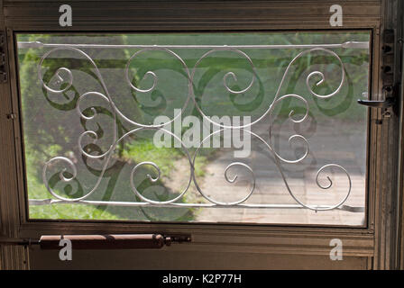 Mitte des Jahrhunderts dekorative-Gitter auf ein Fenster in der Tür mit Gras und eine Terrasse hinter sich Stockfoto