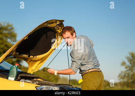 Der Mann prüft den Ölstand im Motor des Autos. Mühe auf der Straße. Reparatur auf der Straße. Stockfoto