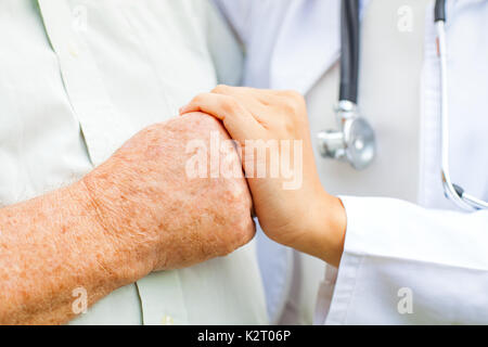 Nahaufnahme junge Ärztin Holding behinderte ältere Menschen die zitternde Hand Stockfoto