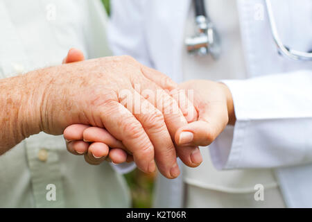 Nahaufnahme junge Ärztin Holding behinderte ältere Menschen die zitternde Hand Stockfoto