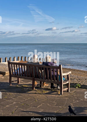 Alte Rentnerehepaar auf sitzen auf hölzernen Sitzbank mit Meerblick am Meer Grand Parade, Eastbourne, East Sussex, England, Großbritannien Stockfoto