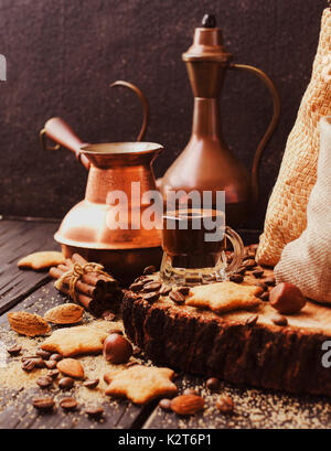 Türkischer Kaffee in einer kleinen Tasse, Plätzchen, Zimt Nüsse und Türken für die Vorbereitung, den selektiven Fokus Stockfoto