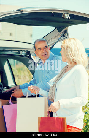 Lächelnd senior Reifes Paar geöffnet bleiben in der Nähe von Booten mit Käufen Stockfoto