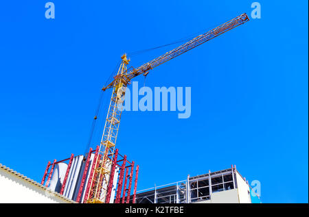 Fragmente von industriellen Gebäuden und einem Turm Kran gegen den blauen Himmel Stockfoto