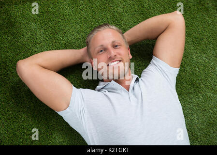 Junge glücklicher Mann liegend auf grünem Gras Stockfoto