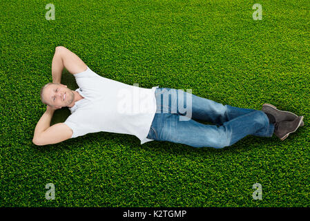 Junge glücklicher Mann liegend auf grünem Gras Stockfoto