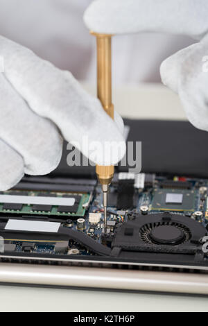 Nahaufnahme der Person Hand in Hand Reparatur Laptop Motherboard Stockfoto