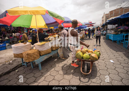 Mai 6, 2017 Otavalo, Ecuador: der Mann, der den Verkauf von Kokosnuss Drink von Schubkarre in der Markt am Samstag Stockfoto