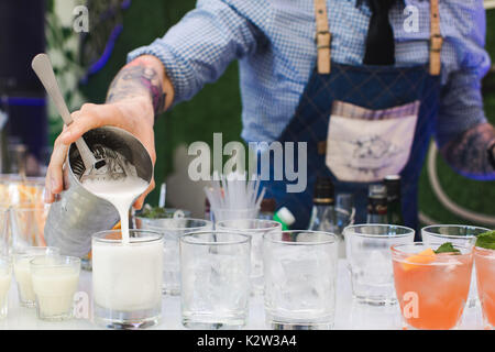 Gesichtslose person Holding metal Shaker und Gießen frisch Cocktails gemacht Stockfoto