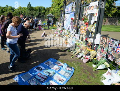 Leute schauen auf Blumen und Würdigungen zum 20. Jahrestag des Todes von Diana, Prinzessin von Wales, außerhalb der Kensington Palace, London. Stockfoto