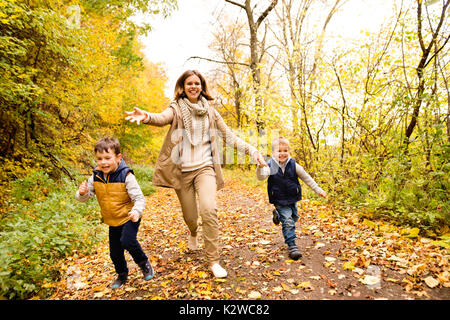 Schöne Mutter mit ihren Söhnen im Herbst Wald. Stockfoto