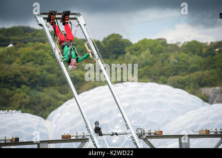 Eddie The Eagle invertiert auf einer massiven 360 Grad human powered Schwingen an das Eden Project in Cornwall geht. Stockfoto