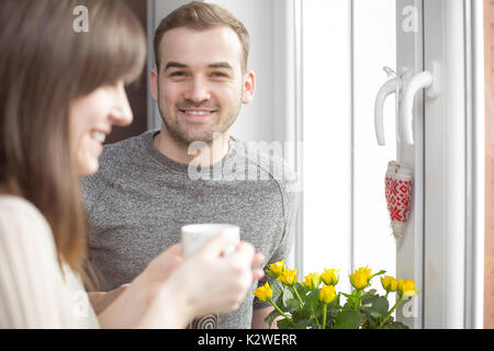 Glückliches Paar stehen am Fenster mit Kaffee Stockfoto