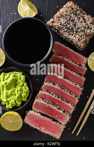 Sesamsamen verkrusteten Thunfisch serviert mit Wasabi und Sauce Nahaufnahme auf dem Tisch. Draufsicht von oben vertikal Stockfoto