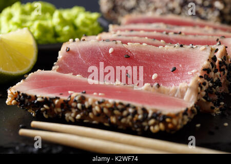 Schön geschnittenen Thunfisch Steak in Sesam und Wasabi, Kalk Makro auf dem Tisch. Horizontale Stockfoto