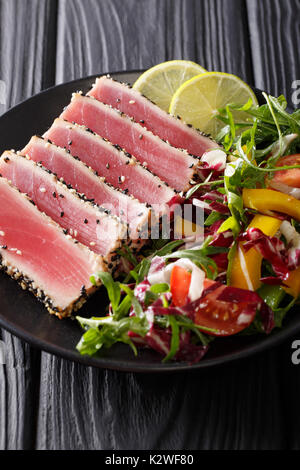 Gebratener Ahi-thunfisch beschichtet Sesamsamen mit Salat auf schwarze Platte closeup. Vertikale Stockfoto