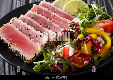 In Scheiben geschnittene Steak von Thunfisch in Sesam und einem Salat von frischem Gemüse close-up auf einem Teller. Horizontale Stockfoto