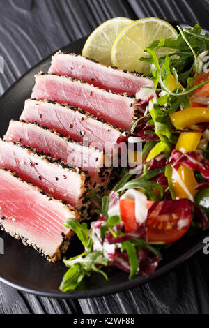 Nahaufnahme von seltenen gebratener Ahi-Thunfisch Scheiben mit frischem Gemüse Salat auf einen Teller. Vertikale Stockfoto