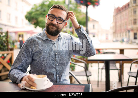 Beschämt lächelnd Mann in einem Cafe sitzen und den Kopf kratzen Stockfoto
