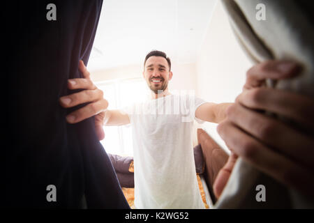 Fröhlicher junger Mann auf der Suche nach einem rechten Kleidung im Schrank. Stockfoto