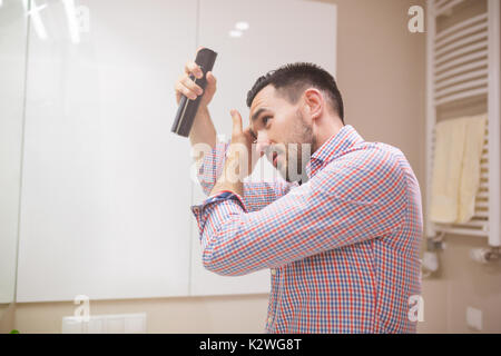 Seitenansicht eines attraktiven Hispanic Mann im Badezimmer Anwendung Haarspray auf seine Frisur. Stockfoto