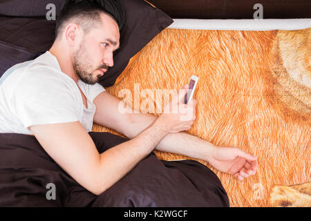 Mansurfing die Net auf sein Smartphone im Bett Stockfoto