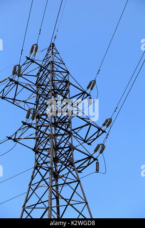 Leitungen und Strommasten gegen blauen Himmel Stockfoto