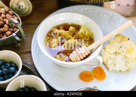 Deko, Essen, Konzept behandeln. Vorderansicht des Schale voller Waben mit housebaked Kuchen verziert und getrockneten Aprikosen auf der glänzenden weißen Platte auf. Stockfoto