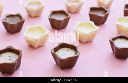 Nahaufnahme von verschiedenen Schokolade Pralinen auf rosa Hintergrund. Stockfoto