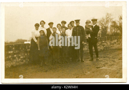 @ 1915, historisches Foto Postkarte aus England, zeigt einen jungen männlichen Soldaten in Uniform mit Stolz posiert mit seinem erweiterten Familie, bevor Sie heaiding in WW1 zu kämpfen. Stockfoto