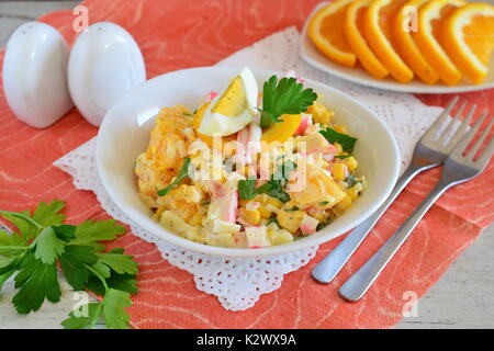 Salat aus Orange, Krabben Fleisch, Eier, Getreide mit Joghurt in einer weißen Schüssel auf einem Tuch Hintergrund serviert. Einfaches Essen. Gesunde Ernährung Konzept. Stockfoto