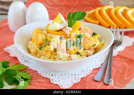 Salat aus Orange, Krabben Fleisch, Eier, Getreide mit Joghurt in einer weißen Schüssel auf einem Tuch Hintergrund serviert. Einfaches Essen. Gesunde Ernährung Konzept. Stockfoto