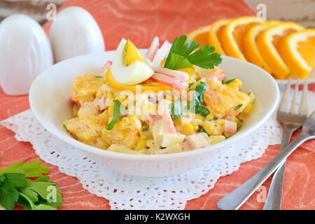 Salat aus Orange, Krabben Fleisch, Eier, Getreide mit Joghurt in einer weißen Schüssel auf einem Tuch Hintergrund serviert. Einfaches Essen. Gesunde Ernährung Konzept. Stockfoto