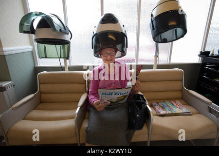 Altersrentner in ihr Haar in einer Haube Haartrockner Lockenstäbe bei einem Damen Friseur, England tragen getrocknet, Vereinigtes Königreich Stockfoto